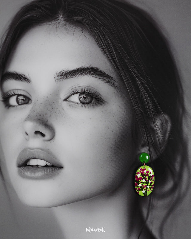 A woman wears the Baaghani handmade drop earrings, highlighting the lively floral design with white and magenta buds on a green base, showcasing the craftsmanship and charm of these statement accessories — Muselot.