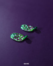Baaghani green floral drop earrings laid flat on a textured surface, highlighting the delicate floral accents and the handcrafted green base that brings out an earthy, graceful charm — Muselot.