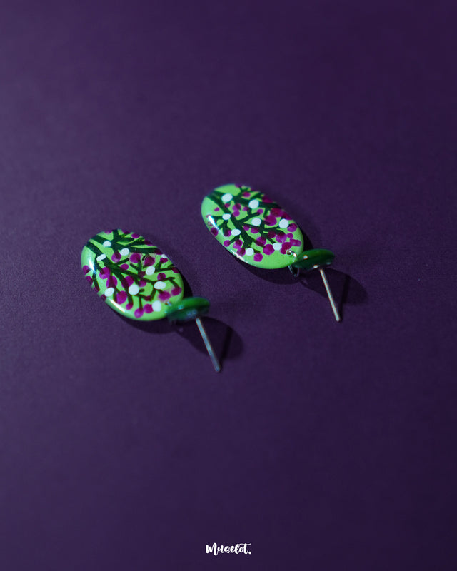 Close-up view of Baaghani green floral drop earrings showing fine detailing of the magenta and white flower petals against a soft green base, highlighting the handmade craftsmanship and elegant design — Muselot.