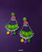 Baharaan green chandbali earrings placed against a purple background, highlighting their crescent shape, vibrant detailing, and handcrafted charm that showcases a blend of tradition and playfulness — Muselot.