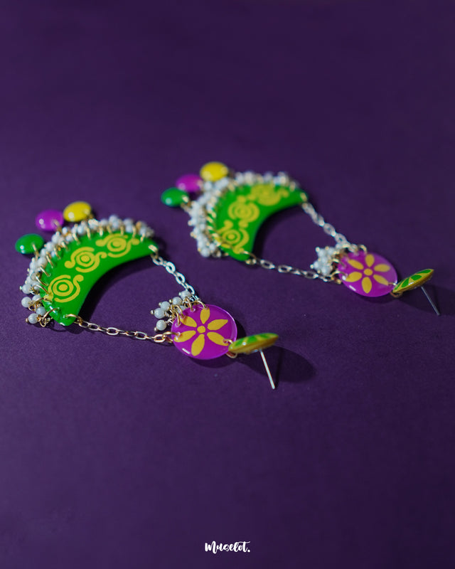 Baharaan green chandbali earrings displayed against a purple background, highlighting the bold crescent design, delicate green floral patterns, and golden detailing that showcase traditional craftsmanship with a festive flair — Muselot.