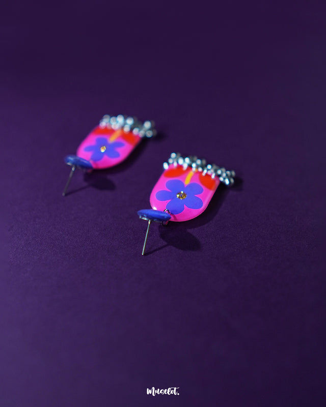 Benazir floral earrings displayed with a focus on their detailed purple flowers and vibrant red leaves, set against a rich purple background, offering a sophisticated touch to any ensemble — Muselot