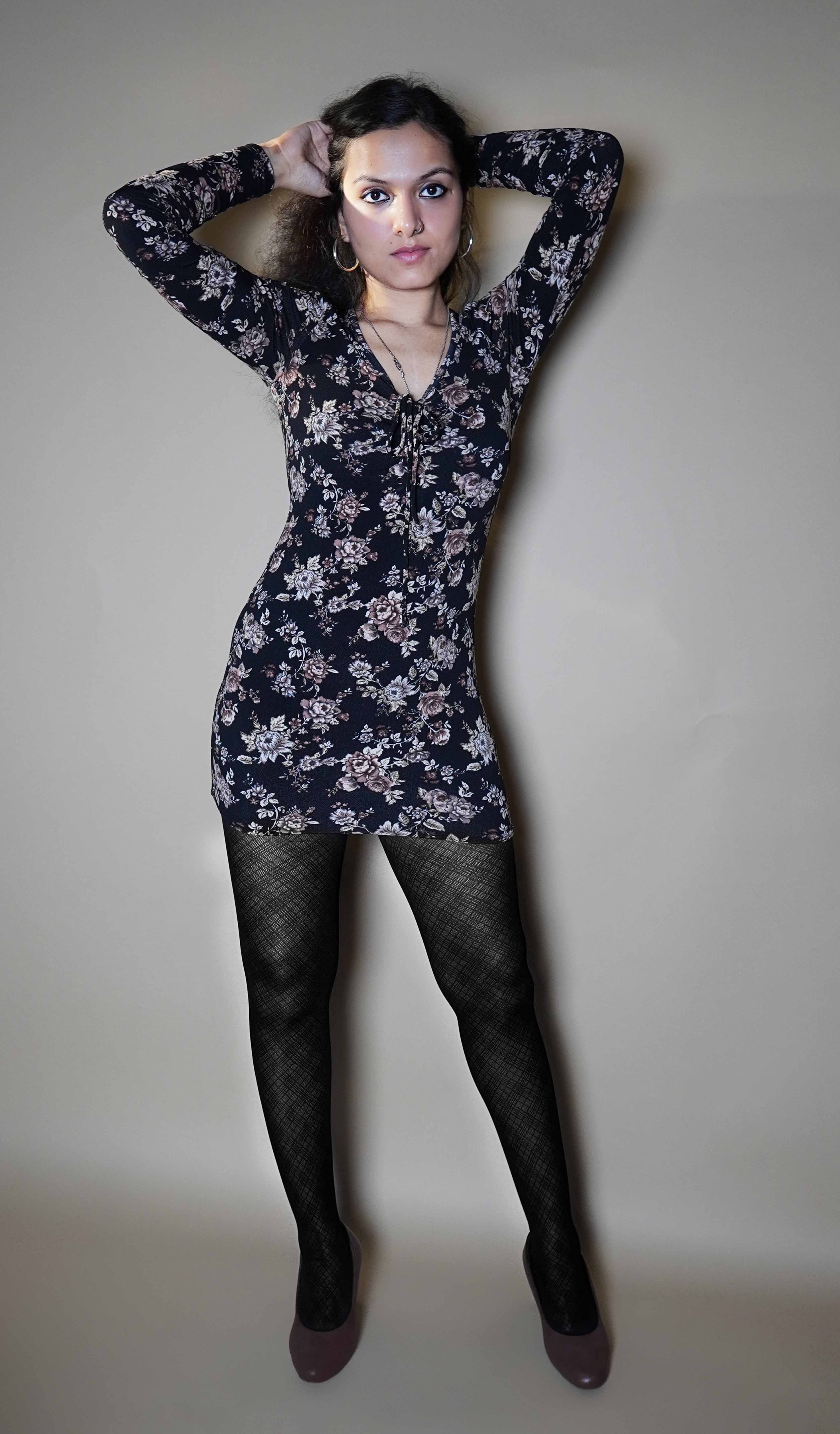 A model wearing sheer black sexy pantyhose, posing with her hands gently grabbing her hair behind her head, highlighting the trendy modern look-Muselot