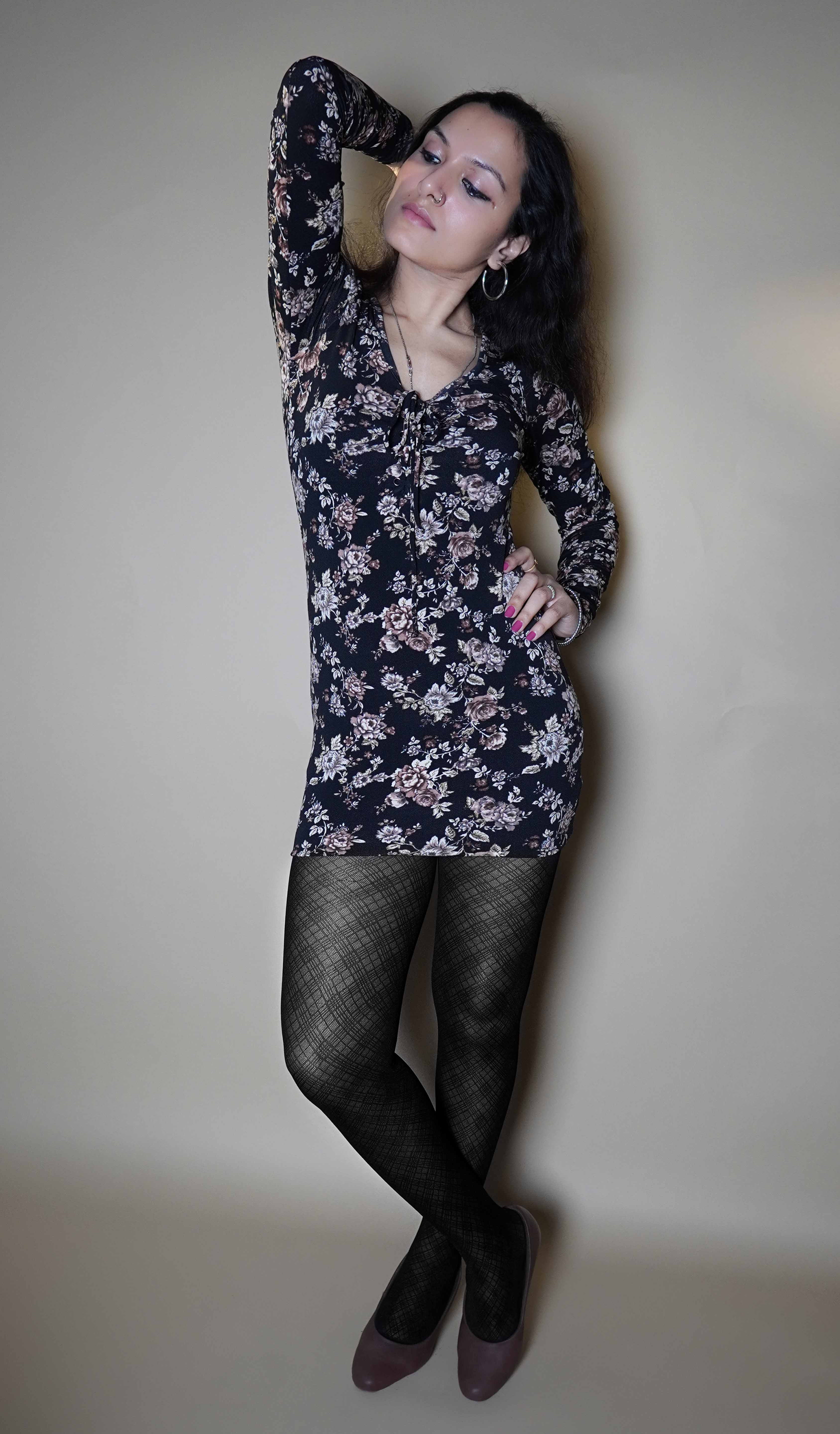 A model wearing black colored sheer pantyhose, posing with her hand up behind her head and other on her waist as she stands slightly sideways, showcasing the confidence that her tights bring-Muselot