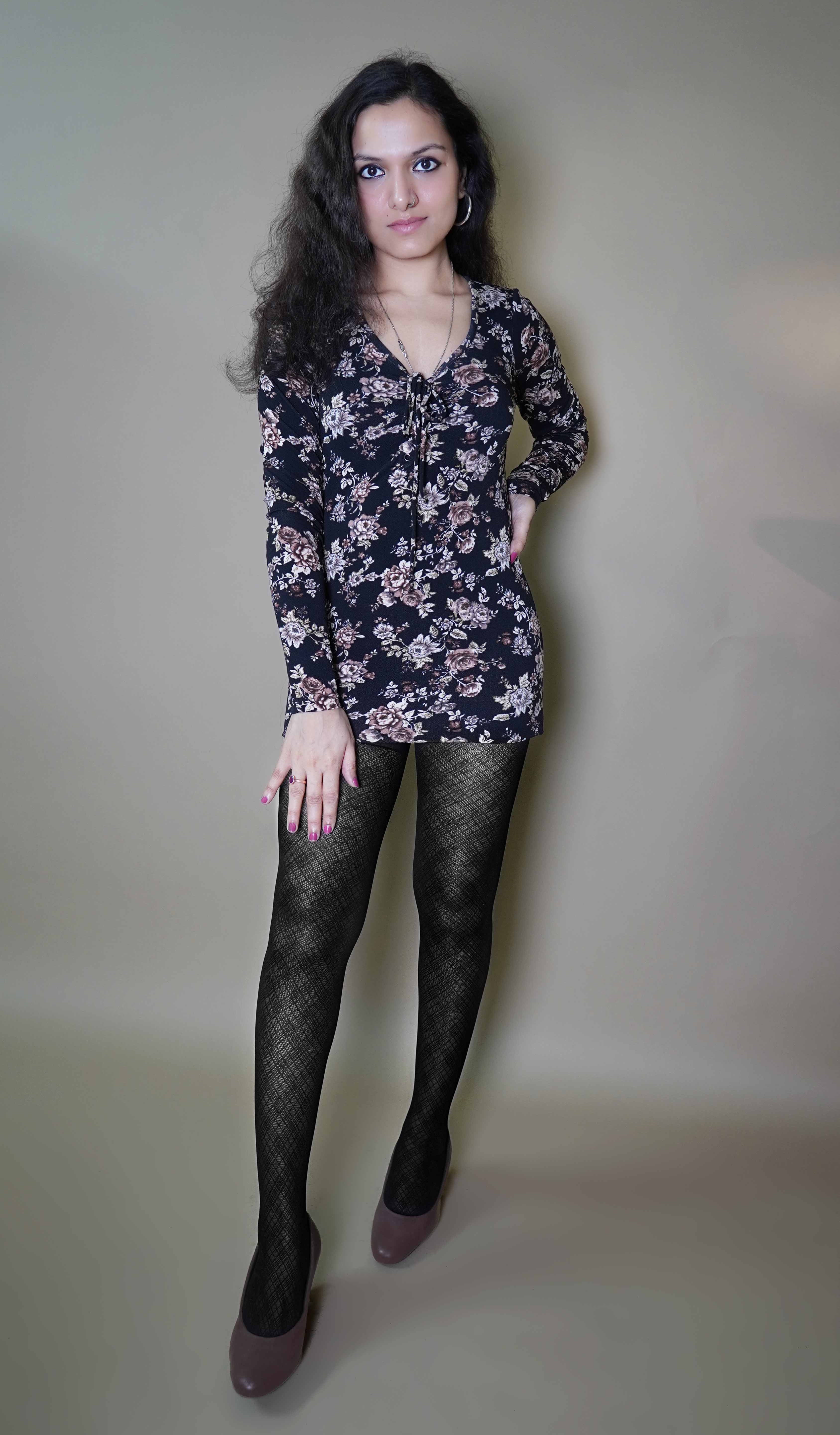 A woman wearing black lattice patterned sheer stockings, posing with her hand on her thigh and other on her waist, highlighting the durable smooth material-Muselot