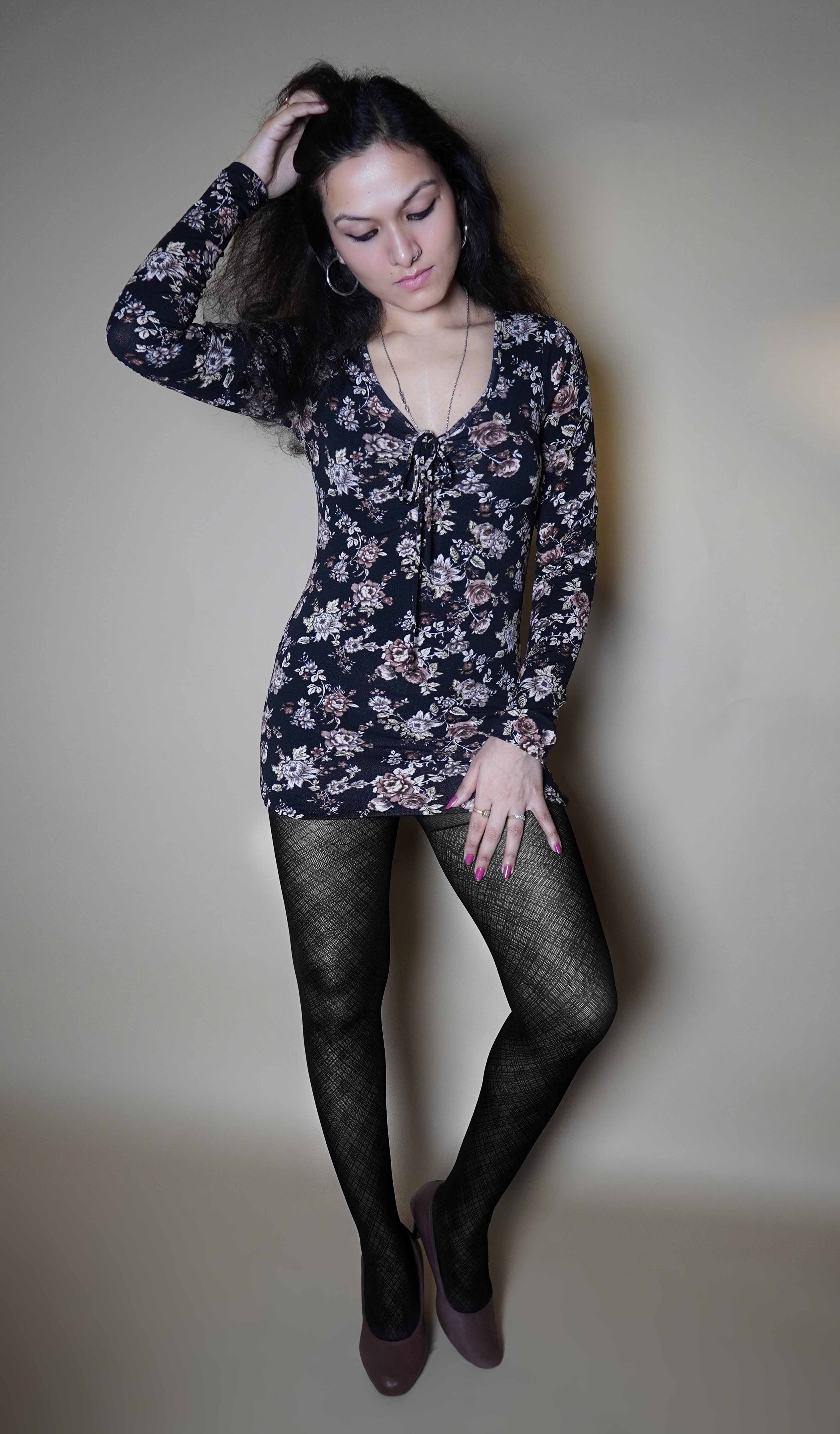 A woman wearing black girl's patterned sheer stockings, posing with her hand in her hair and other on her thigh, showcasing the perfect modish tights-Muselot