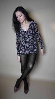 A woman wearing stretchable patterned sheer tights for women, posing with her legs crossed as she slightly bend forward, highlighting the classy pretty look-Muselot