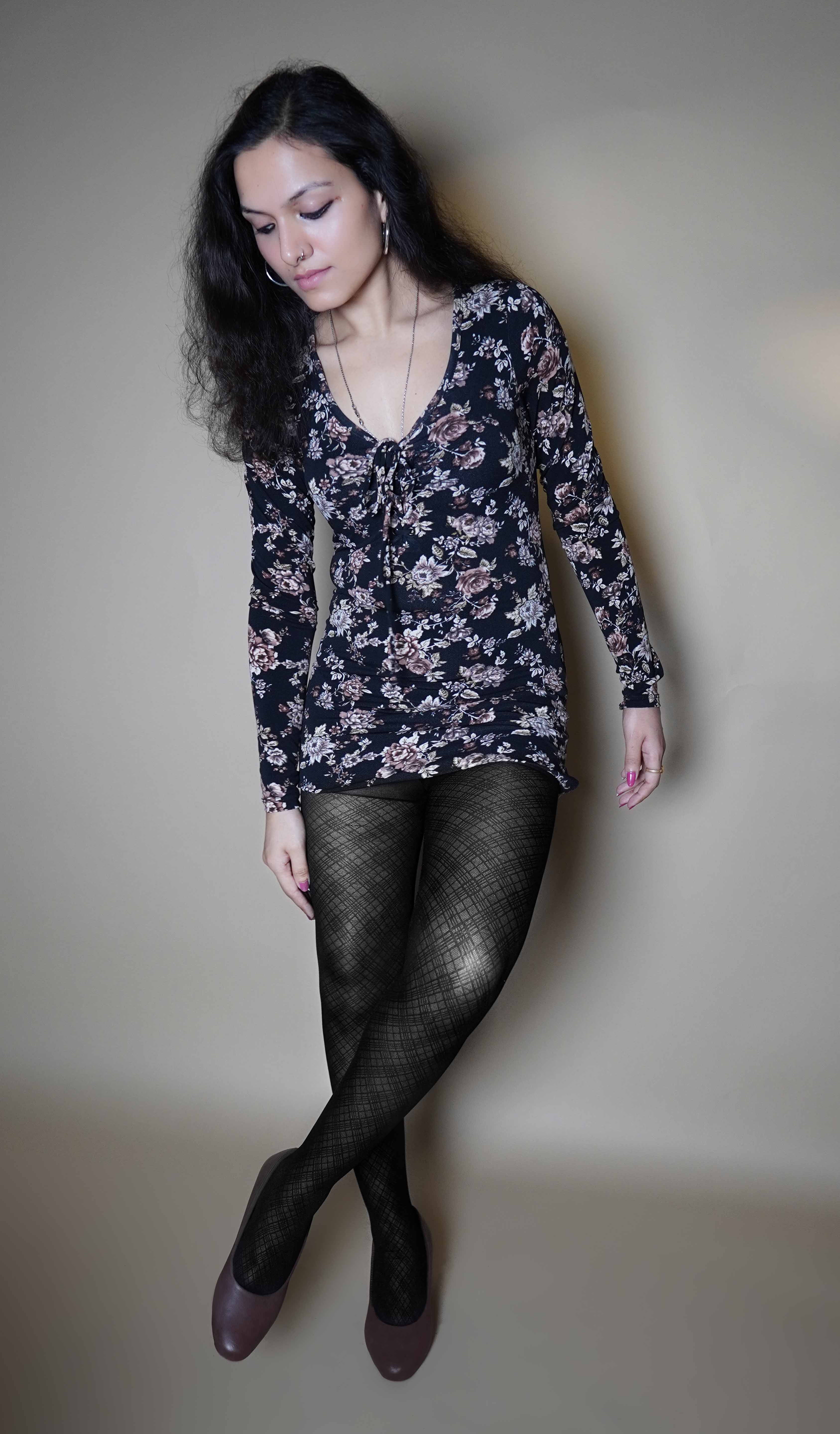 A woman wearing stretchable patterned sheer tights for women, posing with her legs crossed as she slightly bend forward, highlighting the classy pretty look-Muselot