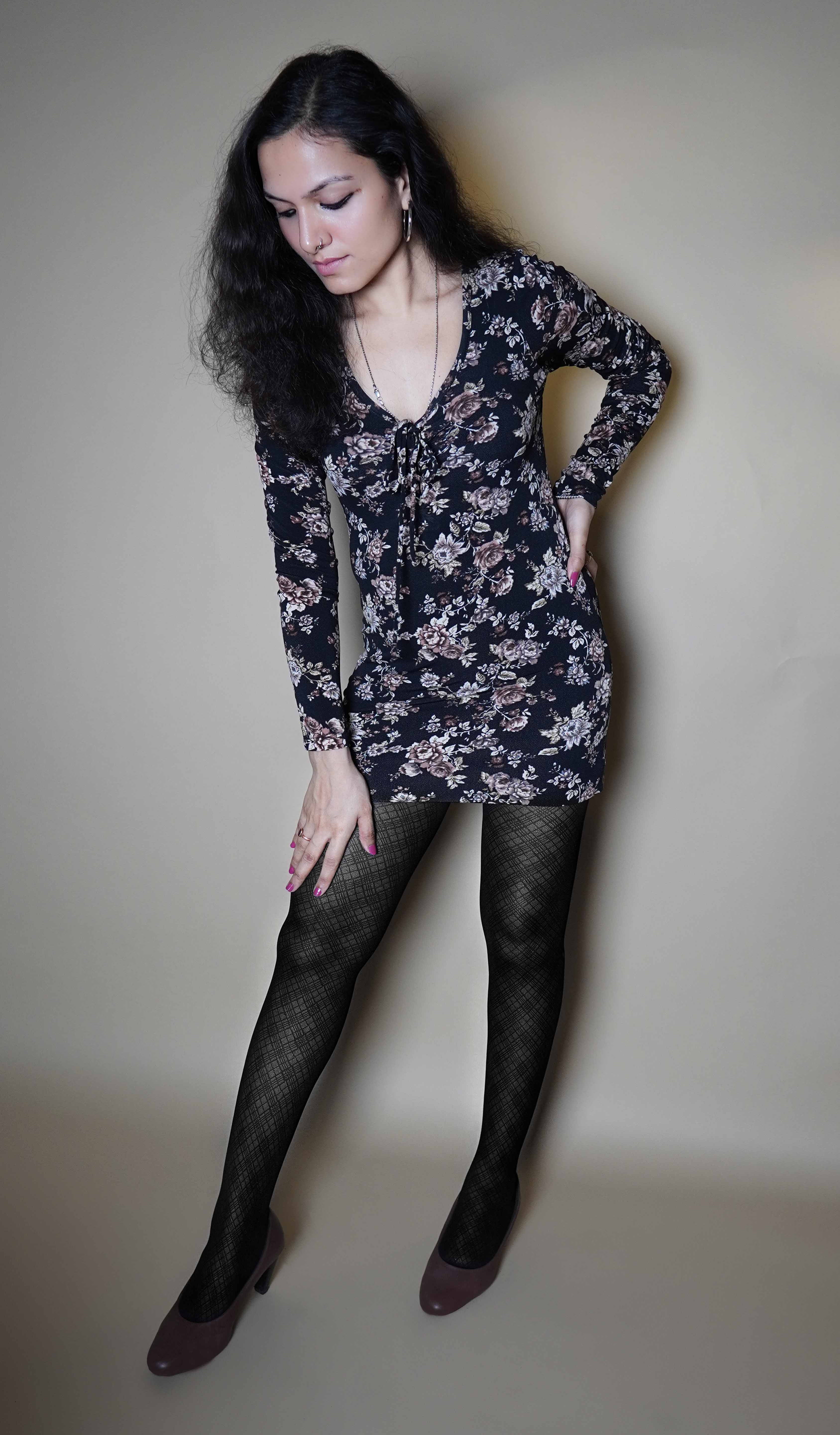 A woman wearing black moisture wicking sheer tights, posing with her hand on her waist and other on her thigh as she bends slightly forward, showcasing the perfect pattern of the stockings-Muselot