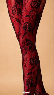 Close-up of black designer lace layered over red opaque stockings, showcasing the detailed rose motifs, leaves, fine mesh and floral pattern of Sinful Rose – Muselot.