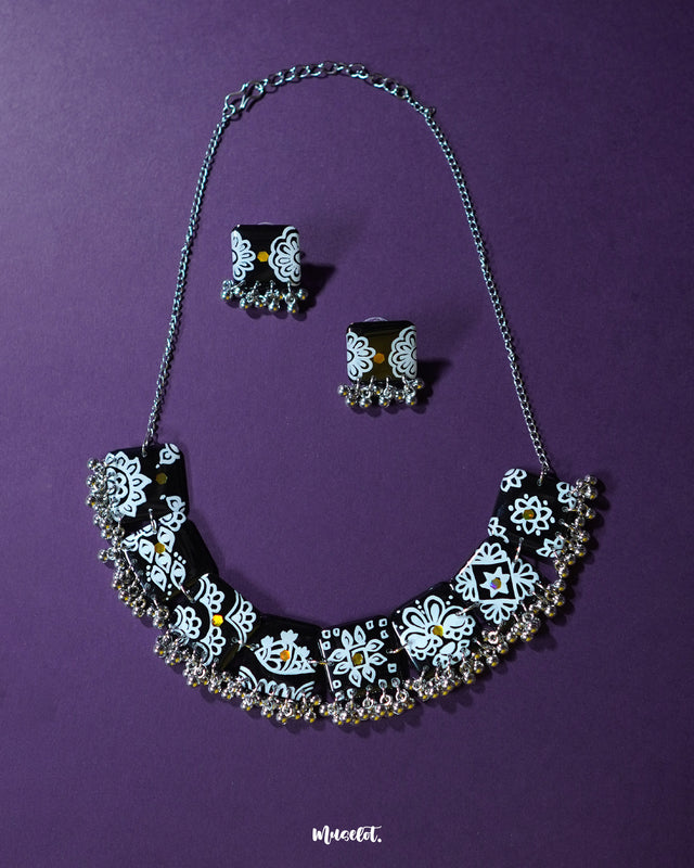 Black floral jewelry set featuring hand-painted floral motifs and oxidized metal detailing, laid out against a soft background to highlight its intricate craftsmanship and bold traditional charm — Muselot