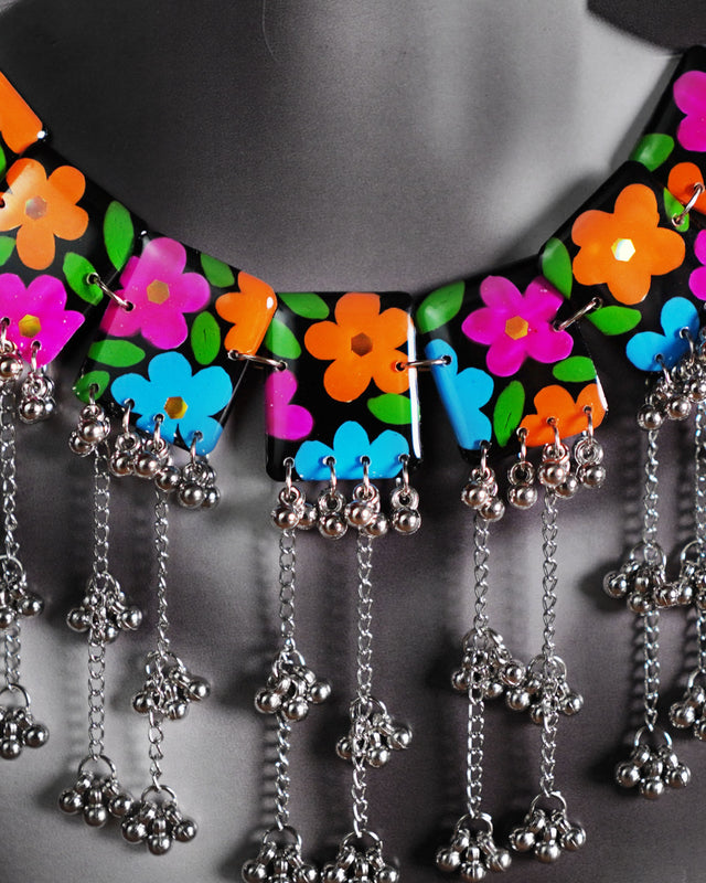 Close-up view of the black floral necklace set worn by a model, showcasing the intricate floral accents and beaded craftsmanship that gracefully trace the neckline, adding a refined touch to the overall ensemble — Muselot
