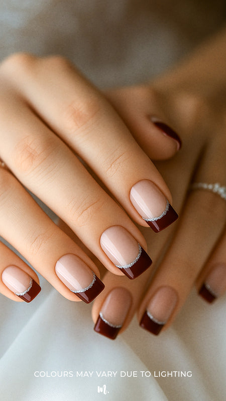 A model’s hand showcasing Cherry Moon French Tip nail stickies, featuring deep maroon glossy tips accented with a fine silver glitter curve over a nude natural base, highlighting the bold yet sophisticated charm of this French manicure design – Muselot.
