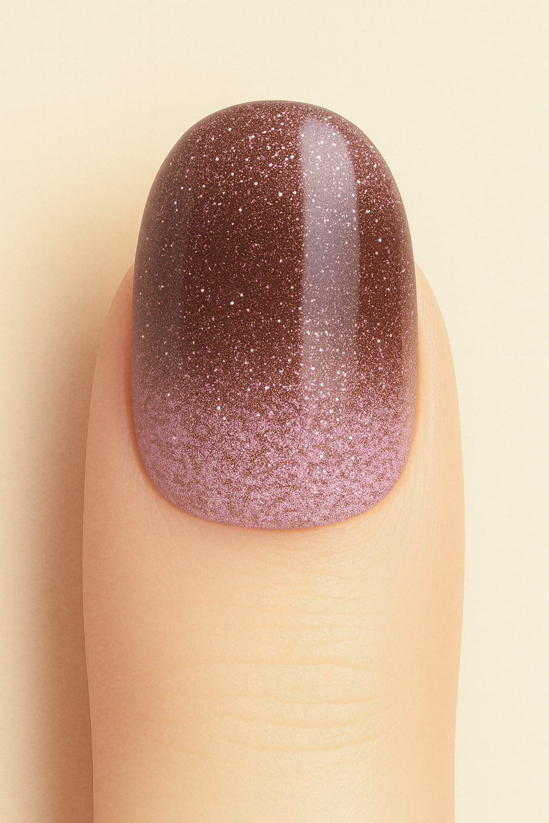 A close-up shot of a model’s finger wearing Choco Plum Glitter Ombre nail stickies, showcasing the smooth gradient that shifts from soft plum to deep chocolate brown, highlighted with fine sparkling glitter for a rich ombre effect that adds depth, elegance, and a salon-style glossy finish – Muselot.