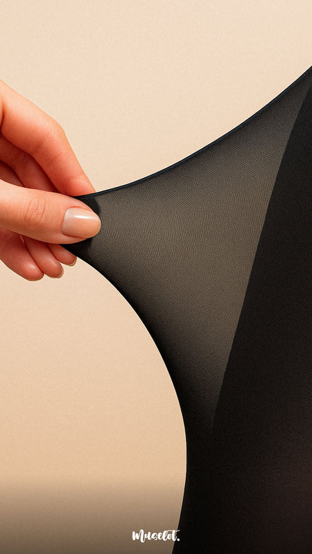 Close-up of a hand stretching the black Muselot sheer effect stocking to show its high elasticity and smooth texture. Set against a beige background, this minimal visual highlights the tear-proof strength and ultra-stretch fabric of the premium tights.
