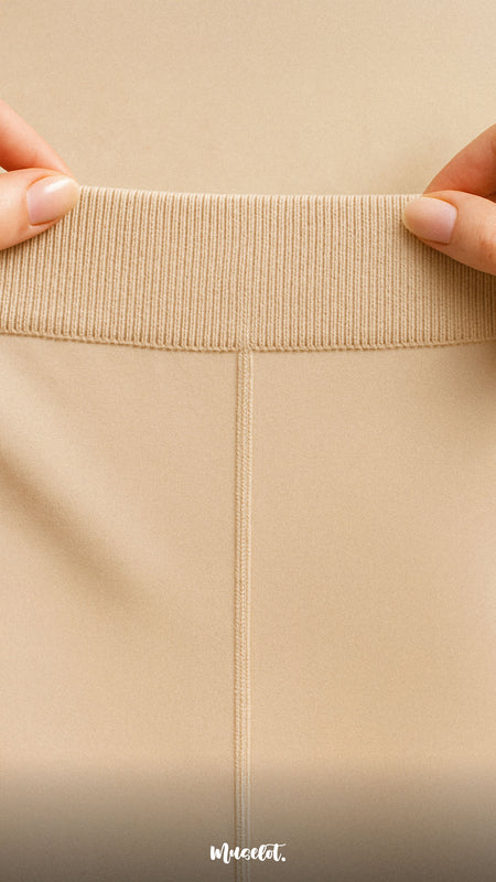 Close-up of a nude Muselot stocking waistband held between two hands, highlighting its soft, stretchable, ribbed texture and flat seam design for maximum comfort and grip.