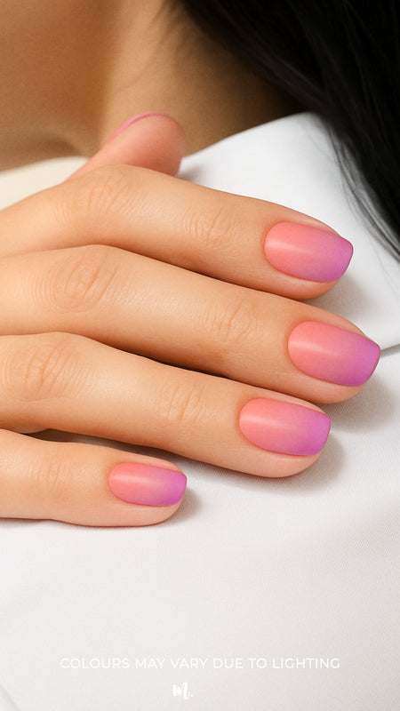 A model’s hand styled with Coral Kiss Ombre Nail Stickies, showcasing a smooth gradient blend from bright coral pink to soft lilac-purple, highlighting the glossy finish and effortless elegance of ombre nail art for a chic, salon-like look – Muselot.