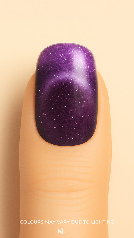 A close-up shot of a model’s finger wearing Cosmic Gaze Ombre nail stickies, showcasing a deep galaxy-purple shade that fades into subtle gradients, highlighted with tiny star-like specks for a celestial effect, emphasizing the bold and cosmic allure of ombre glitter nail art – Muselot.