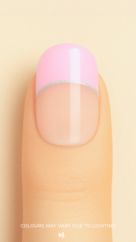 A close-up shot of a model’s finger featuring Crowned Petal French Tip nail stickies, designed with a glossy pastel pink tip accented by a sleek silver glitter line over a natural nude base, creating a chic and feminine French manicure look – Muselot.