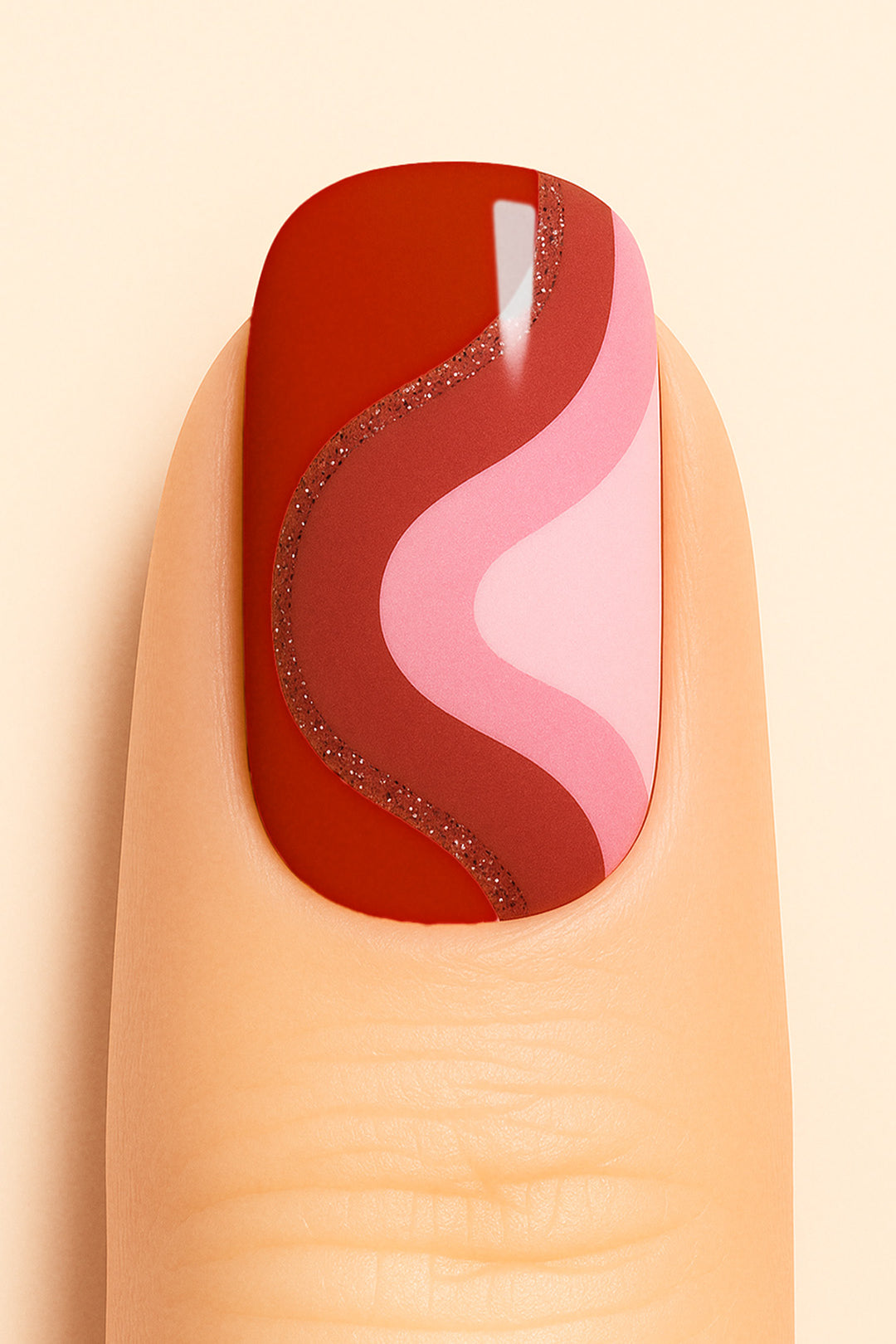 A close-up of a finger wearing Dried Rose Nail Stickies, featuring bold wavy patterns in deep red, dusty rose, and soft pink, outlined with a touch of glitter for added elegance. The design creates a retro-modern vibe, making the manicure stand out with its artistic curves and chic finish – Muselot.