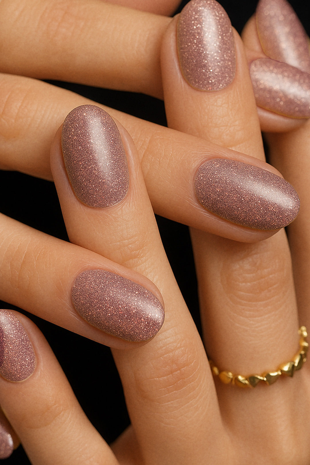 A shot of model hands wearing Dusty Rose Glitter nail stickies, showcasing the soft rose-pink shade filled with fine glitter sparkles, highlighting the shimmer and elegance of minimal nail art in a glossy salon-style finish – Muselot.