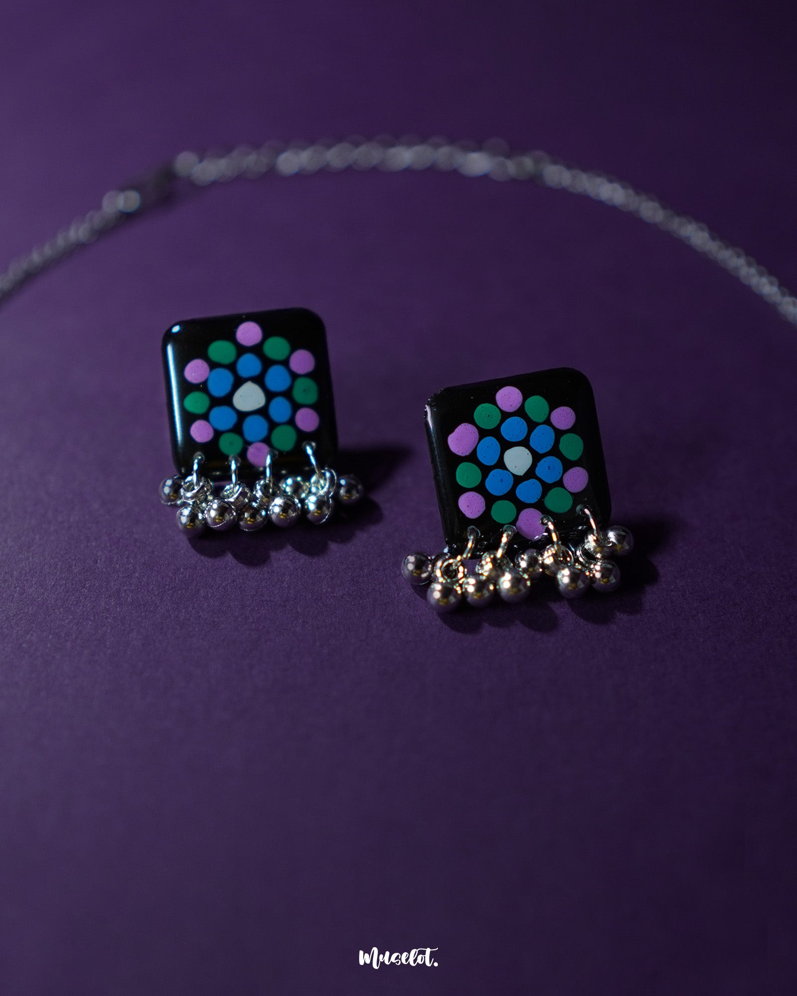 Pair of Falak black handmade earrings, featuring teal and purple polka motifs with silver ghungroo detailing, showcased on a plain backdrop – Muselot.