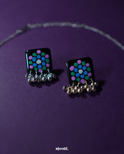 Pair of Falak black handmade earrings, featuring teal and purple polka motifs with silver ghungroo detailing, showcased on a plain backdrop – Muselot.