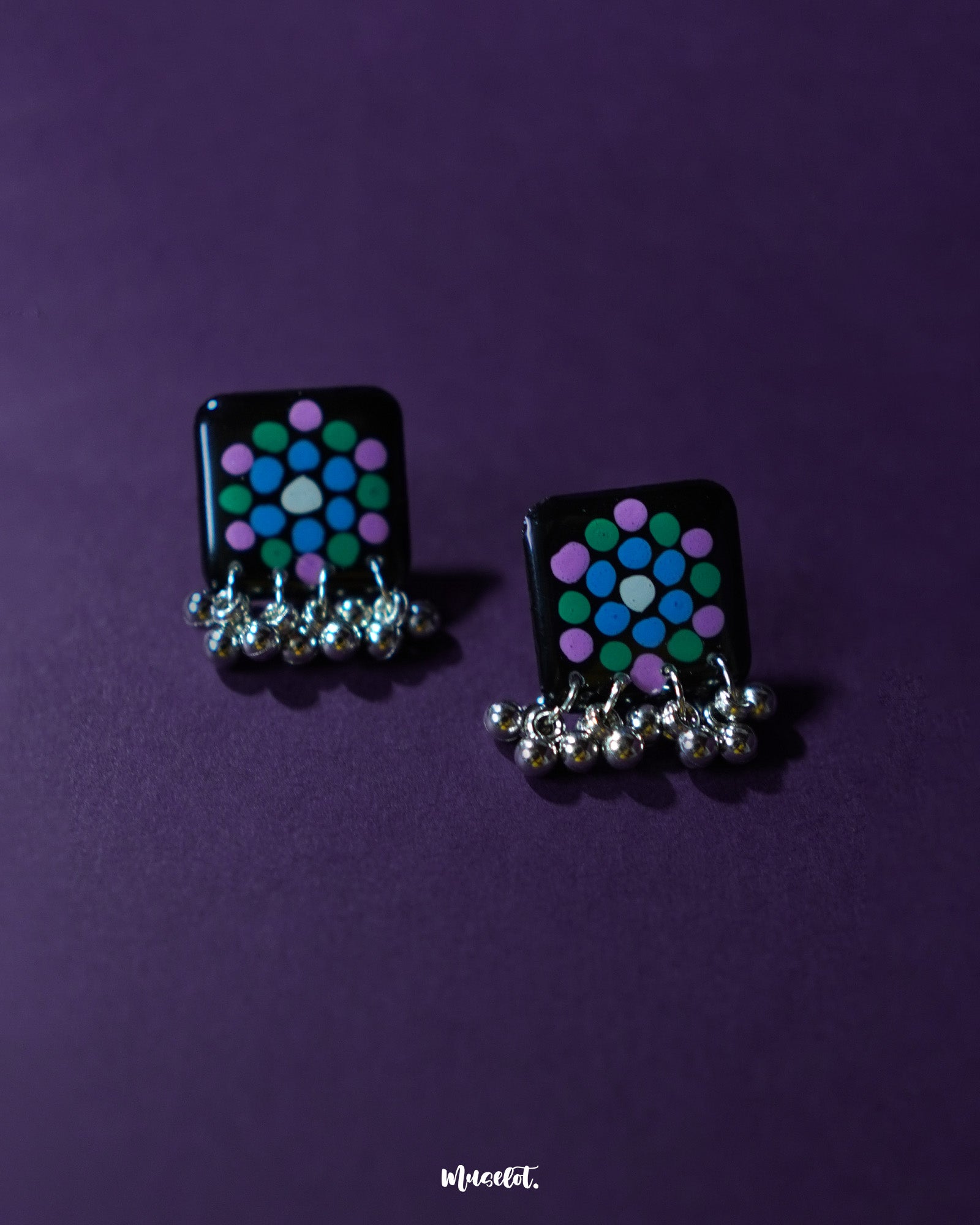Falak black handmade earring with teal and purple polka design and silver ghungroo drops, displayed against a purple background – Muselot.