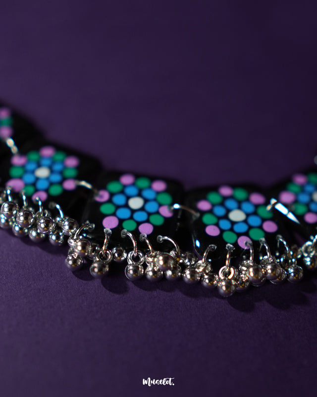 Close-up of Falak black handmade necklace, highlighting hand-painted teal and purple polka tiles with silver ghungroo edging on a neutral background – Muselot.