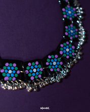 Falak black handmade necklace laid flat, featuring square hand-painted tiles with teal and purple motifs and silver ghungroo trim on a plain backdrop – Muselot.