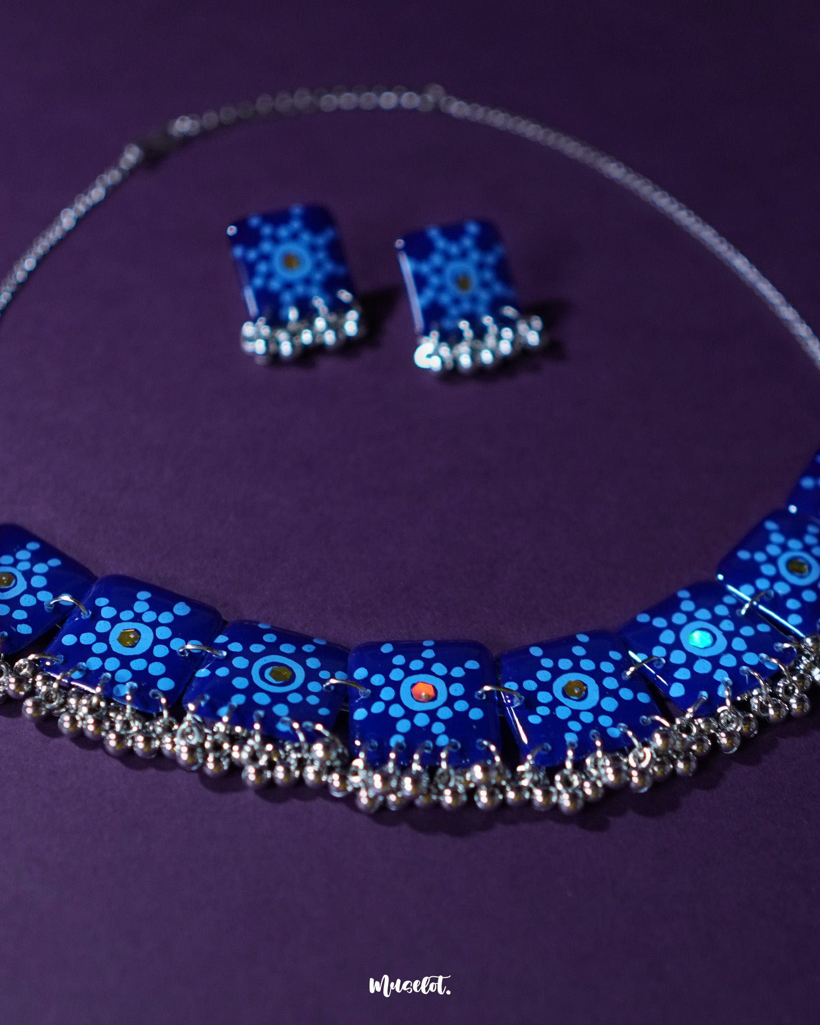 Falakzaar blue necklace and earring set featuring delicate hand-painted floral patterns in white and sky blue on a deep blue base, highlighting the intricate craftsmanship and showcasing graceful ethnic charm — Muselot.