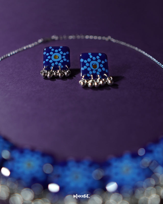 Falakzaar blue floral earring set placed on a light backdrop, highlighting intricate floral detailing and showcasing the harmonious blend of blue and soft pastel shades — Muselot.