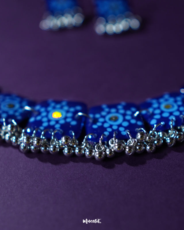 Falakzaar blue floral necklace and earring set displayed flat against a minimal background, highlighting the delicate thread work and showcasing the statement charm of handcrafted accessories — Muselot.