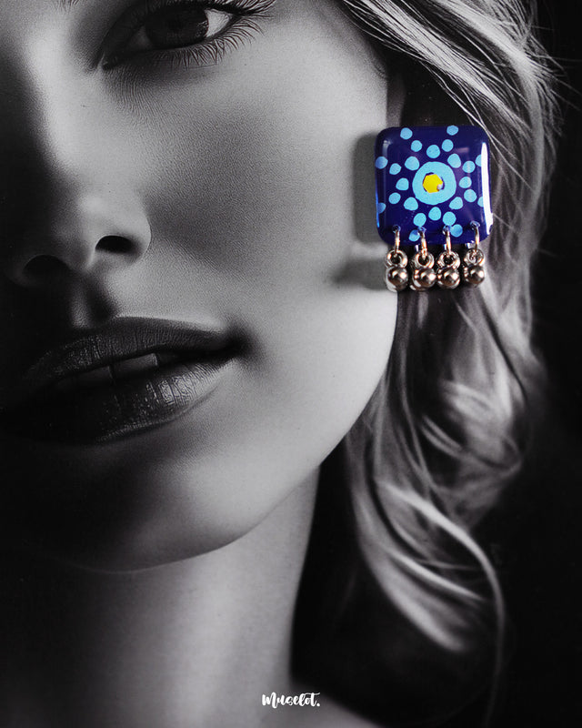 A model flaunts the Falakzaar blue earrings from the set, highlighting the vibrant hand-painted mandala motifs and silver bead drops that add a traditional yet trendy charm — Muselot.