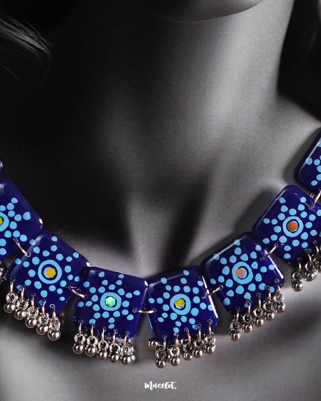 A close-up shot of the model wearing the Falakzaar blue necklace, showcasing the intricate hand-painted patterns and silver bead detailing that highlight its artisanal charm and vibrant elegance — Muselot.