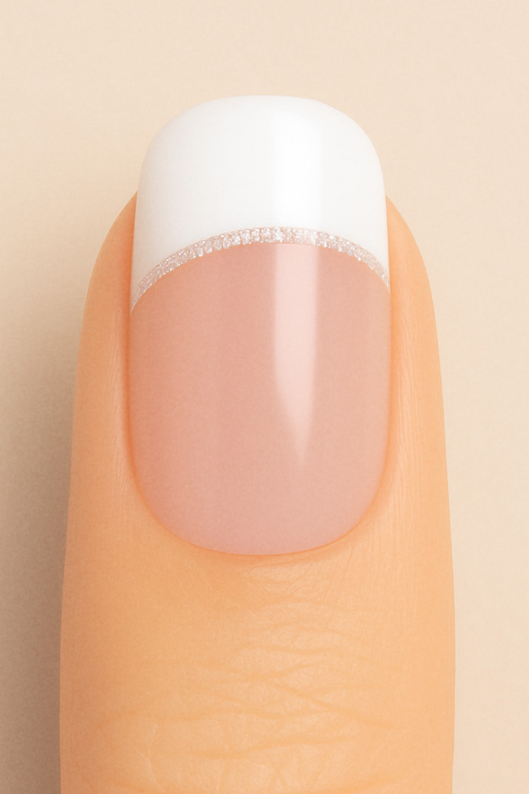 A close-up of a model’s finger featuring Frosted Charm French Tip Nail Stickies by Muselot, designed with a classic white French tip accented by a fine line of subtle glitter, giving a timeless and elegant manicure look with a glossy finish.