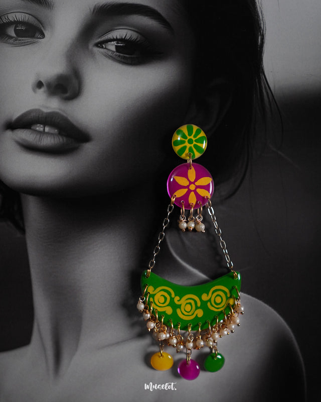 A closeup shot of a model wearing green chandbali earrings with layered detailing and beaded hangings, highlighting festive vibrance and showcasing traditional artistry in a modern colour story — Muselot.