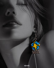 Close-up of a woman wearing the Gulaftab floral hook earrings, highlighting the striking blue and yellow floral pattern and silver bead details that enhance their artistic, handcrafted elegance — Muselot.