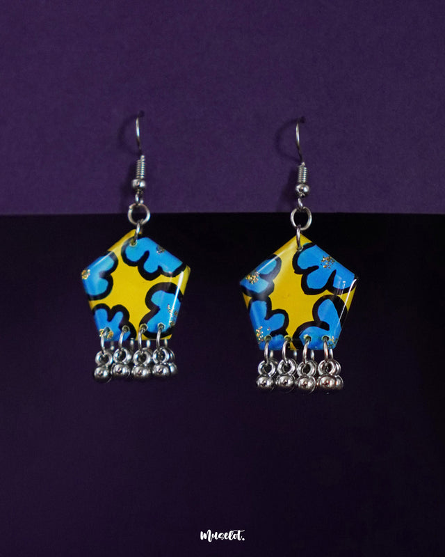 Gulaftab floral hook earrings featuring a vibrant yellow and blue abstract floral design with silver-toned dangling beads, set against a dual purple backdrop — Muselot.