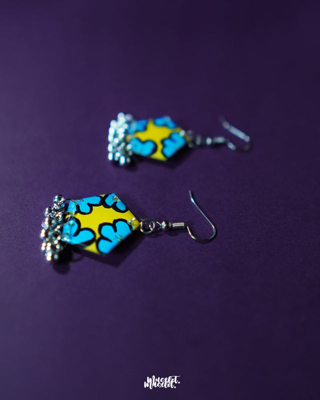 A focused shot of the Gulaftab hook earrings from the side, highlighting the delicate curve of the hooks and the vivid floral accents in yellow and blue, showcasing the handcrafted elegance — Muselot.