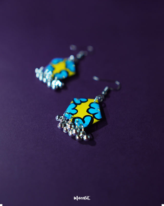 A zoomed-in view of the Gulaftab hook earrings, highlighting the detailed yellow and blue floral design with soft brush strokes, showcasing the finesse of handcrafted artistry — Muselot.