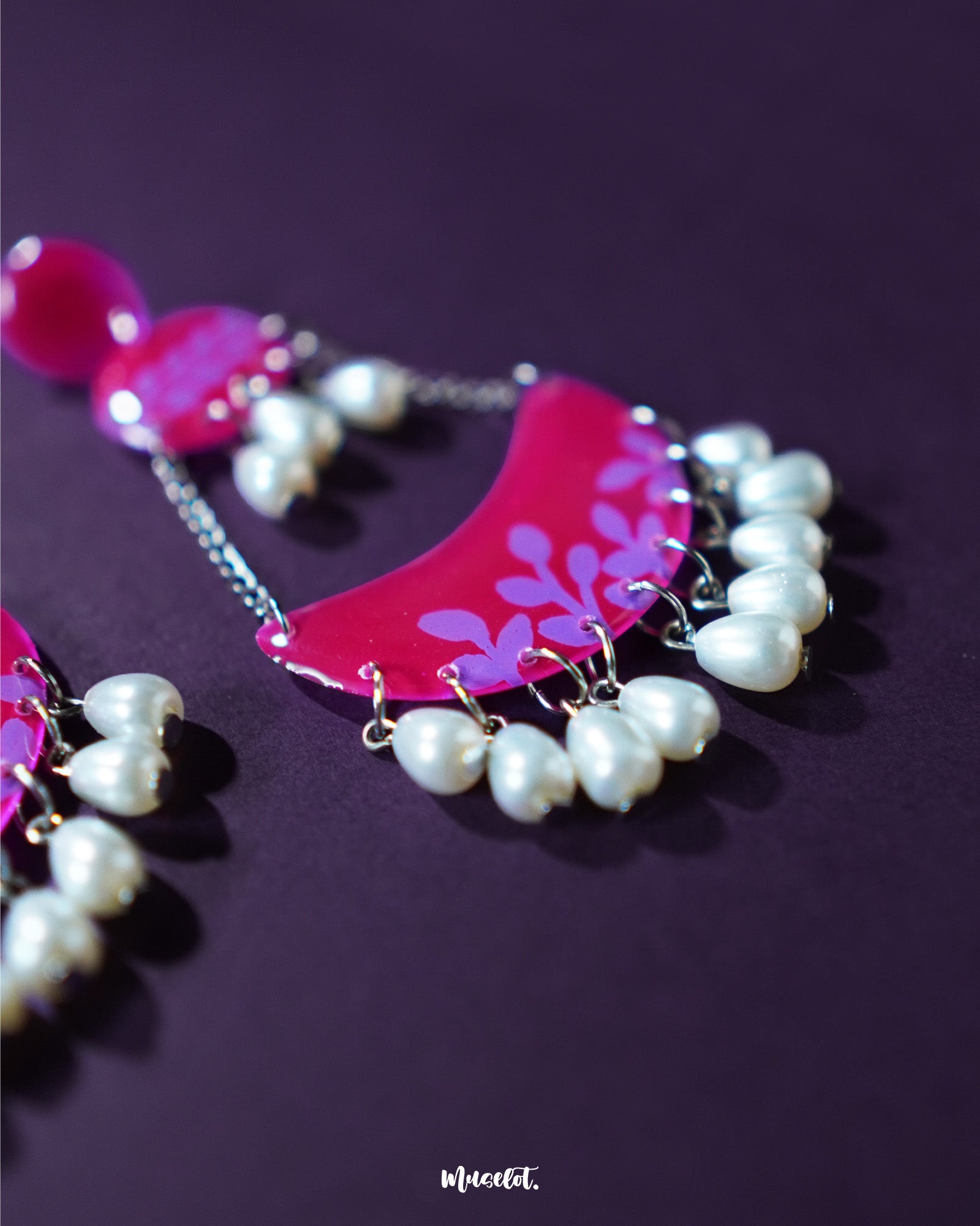 A close-up of the Gulfaam pink pearl chandbali earrings showcasing their layered magenta crescents, delicate floral engravings, and pink pearl dangles that exude elegance and grace — Muselot.