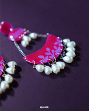 A close-up of the Gulfaam pink pearl chandbali earrings showcasing their layered magenta crescents, delicate floral engravings, and pink pearl dangles that exude elegance and grace — Muselot.
