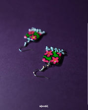 Gulnaar handmade floral hook earrings with rectangular charms displaying vivid pink and red flowers on a green background outlined in black, accented with delicate silver bead tassels, beautifully presented to showcase their colorful and intricate craftsmanship – Muselot.