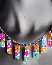 A close-up of the model’s neckline showcasing the Gulraas handmade floral necklace set, highlighting the vibrant hand-painted floral tiles that drape gracefully, adding a burst of color and whimsy to any outfit — Muselot.