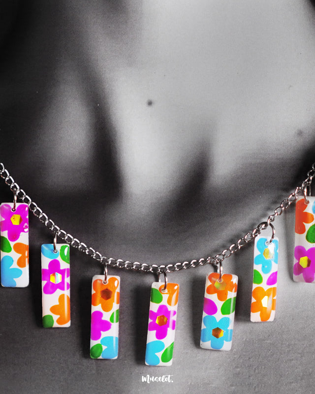 A close-up of the model’s neckline showcasing the Gulraas handmade floral necklace set, highlighting the vibrant hand-painted floral tiles that drape gracefully, adding a burst of color and whimsy to any outfit — Muselot.