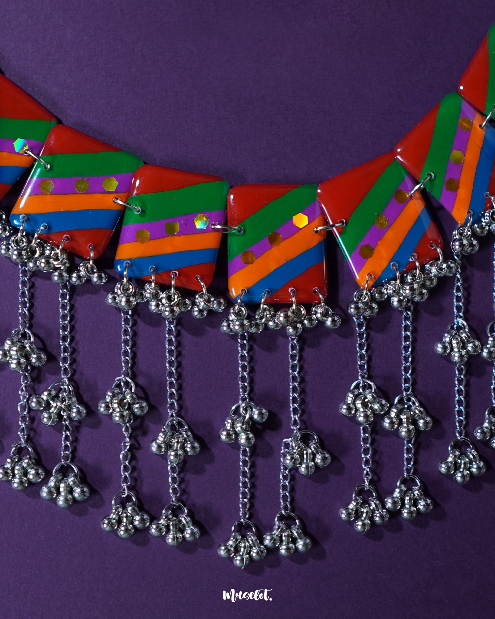 Gulrang multicolor resin jewelry set displayed on a purple background, featuring a silver chain necklace with bold red, green, blue, and purple striped rectangular charms accented with dots and cascading silver bead tassels, paired with matching earrings – Muselot.