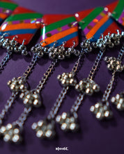 Zoomed-in shot of the Gulrang multicolor resin jewelry set’s ghungroo detailing, showcasing delicate silver bead tassels hanging from bold red, green, blue, and purple striped rectangular charms, highlighting intricate craftsmanship and vibrant design – Muselot.