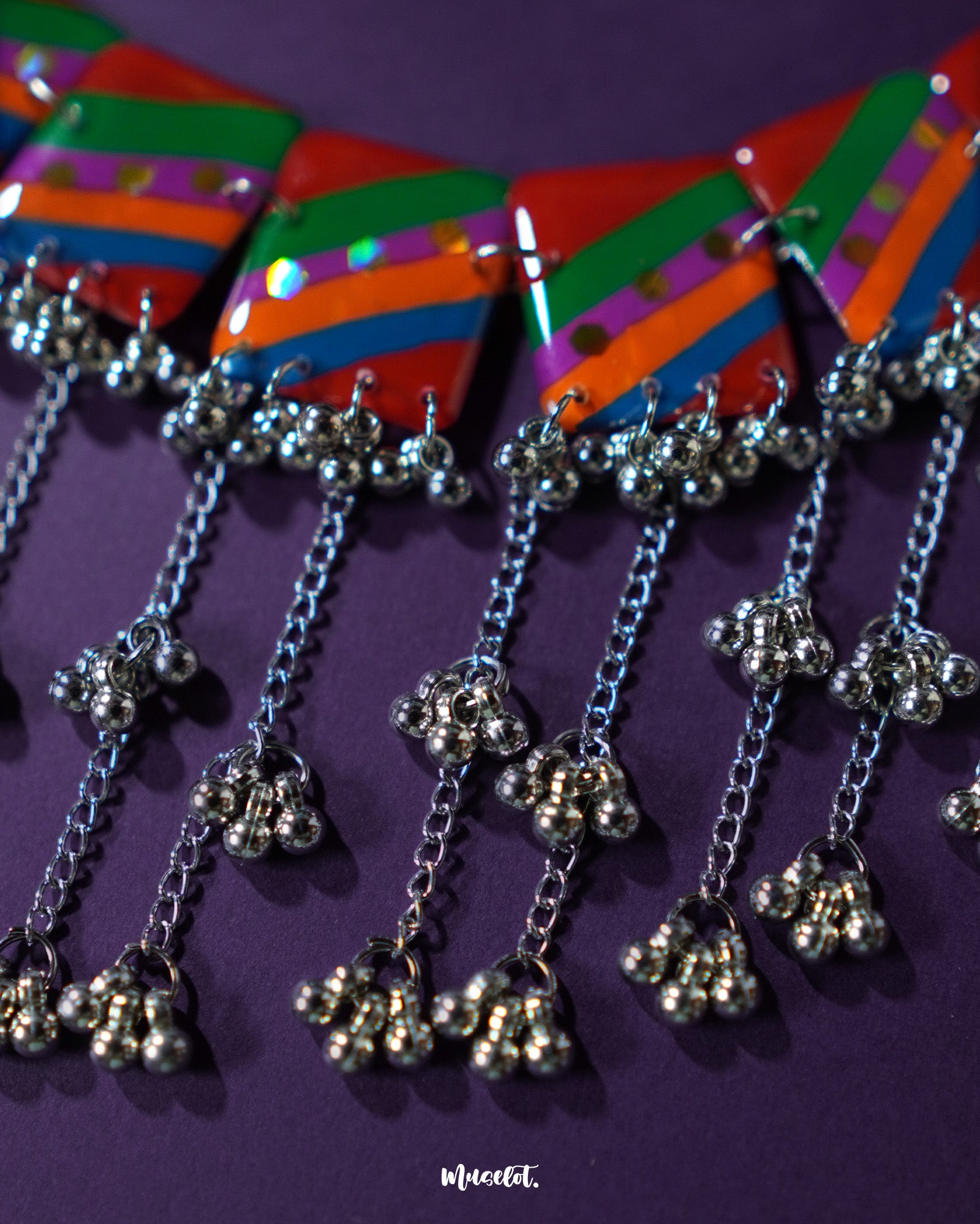 Gulrang multicolor resin jewelry set featuring a silver chain necklace with vibrant red, green, blue, and purple striped rectangular charms accented with dots and silver bead tassels, paired with matching earrings, elegantly displayed on a deep purple background – Muselot.