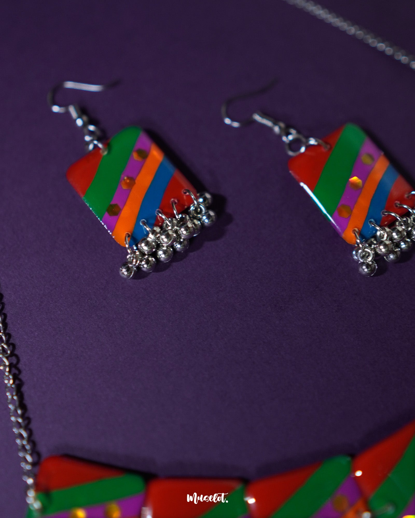 Side-angle shot of the Gulrang multicolor resin earrings, showcasing bold red, green, blue, and purple striped rectangular charms with dotted accents and delicate silver bead tassels, highlighting their vibrant colors and intricate craftsmanship – Muselot.